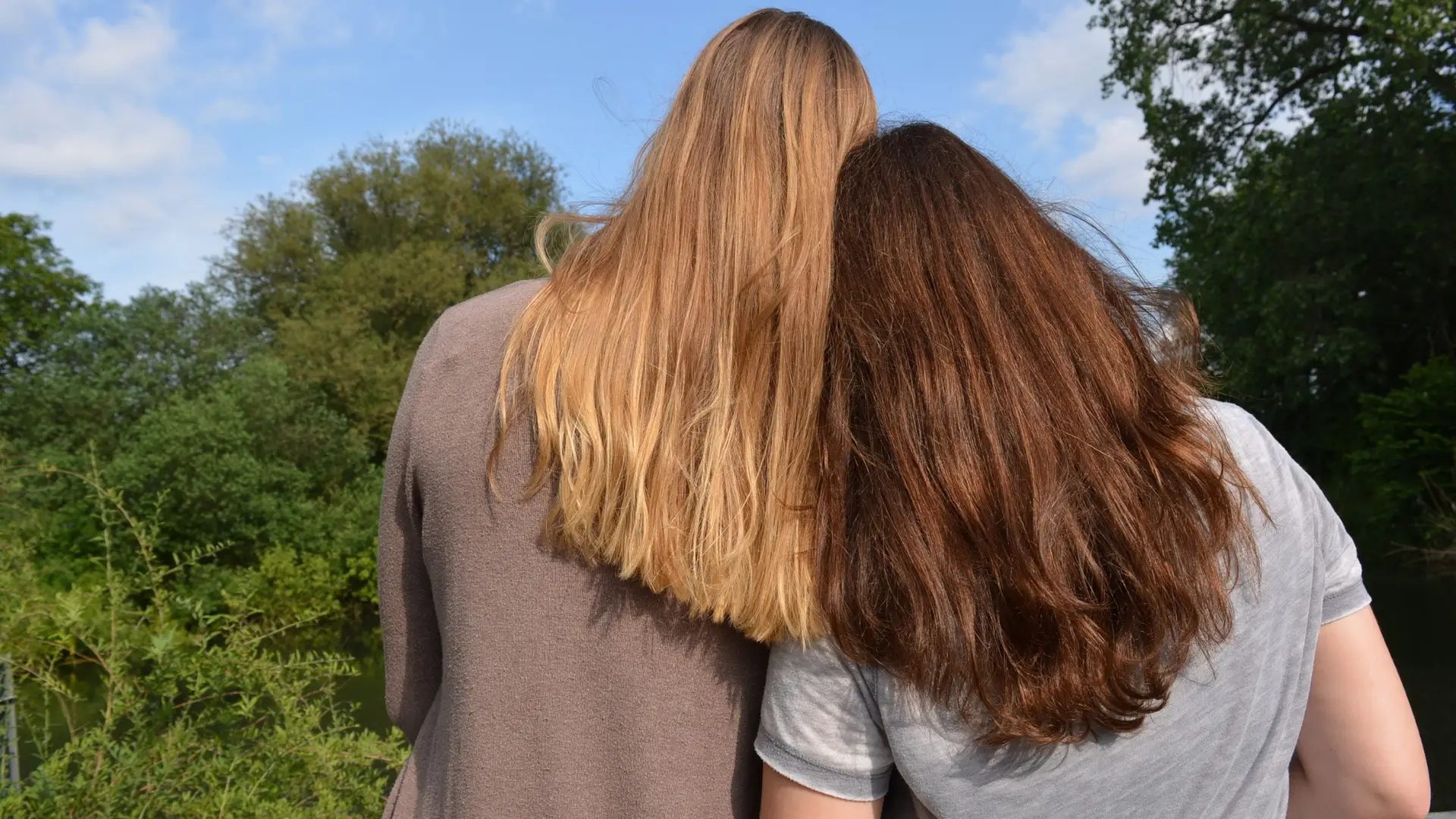 Two girls with long hair leaning on each other