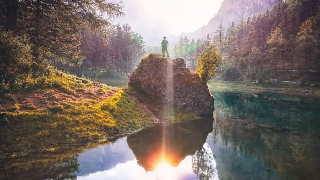 person standing on rock with sunshine in background