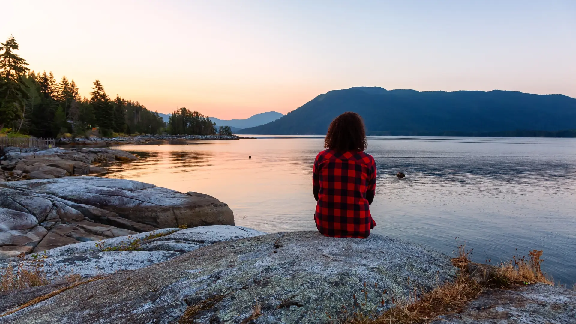 Woman sitting at a lake with back towards the camera