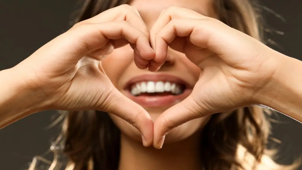 woman smiling with hands in front of her face as a heart